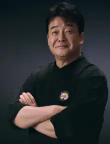 Coloured portrait of South Korean Chef, Baek Jong-won, with his arms crossed