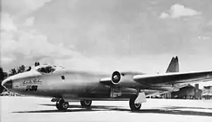 Twin-engined, straight-winged military jet, parked on airfield