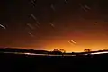 Short streaks of light on a dark sky, showing star trails that were photographed with a long exposure.