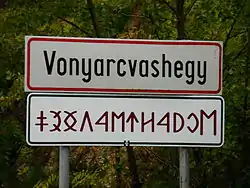 City limit sign in the Hungarian Latin alphabet and Old Hungarian alphabetic script