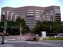 Brown metal and glass building, curved at the center and angled at the sides/