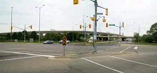 A ground level photo of an intersection, with a series of ramps in the background