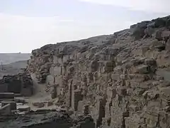 Ruined wall of bricks and a few stones in the desert.