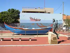 Traditional fishing boat and a sculpture of a diver, in the beach resort Aguda