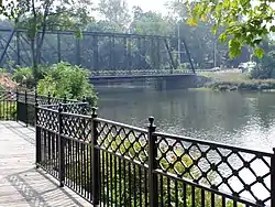 Truss bridge with riverfront walkway in foreground