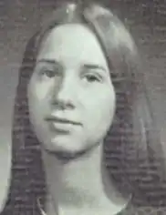 A young white woman with long straight sandy-colored hair parted center