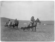 Gros Ventre (Atsina) American Indians moving camps with travois for transporting skin lodges and belongings.