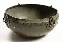 A hanging bowl seen from the side and slightly above, with two hook escutcheons visible on the outside of the rim