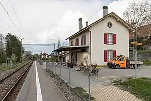 Two-story building with gabled roof next to single track and side platform