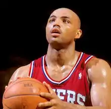 A basketball player, wearing a red jersey, is holding a basketball.