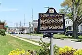 A black historical marker with yellow lettering