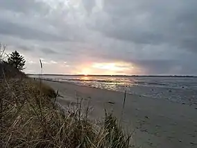 Sunset over a beach at low tide with land in the distance