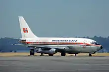 A white, medium-sized jet aircraft with a red and blue cheatline on a tarmac. It has the name "Braathens SAFE" on the side and a Norwegian flag on the tail