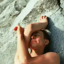 Buck Meek lying against a stone background with his arms over his face