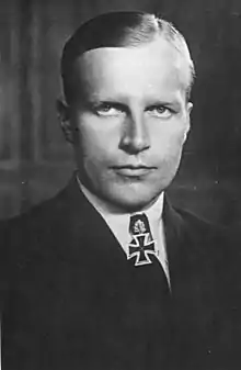 Black-and-white portrait of a man wearing a military uniform, white shirt with an Iron Cross displayed at his neck.