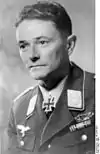 A man wearing a military uniform with an Iron Cross displayed at his neck.