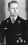 A man wearing a military uniform with an Iron Cross displayed at the front of his uniform collar.