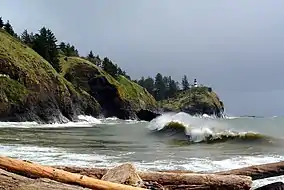 A lighthouse atop a rocky cliff overlooking water