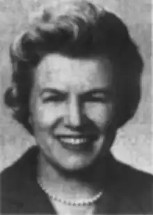 A smiling white woman with hair in a curly bouffant style