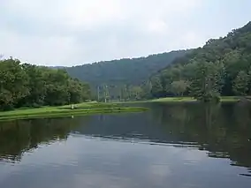 A reservoir surrounded by forested mountain ridges on either side and in the background.