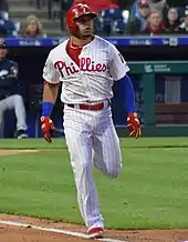 A baseball player in a white uniform with red pinstripes