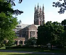 Exterior of red brick bell tower and chapel with Gothic decorative elements