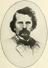 Sepia print of a dark-haired man with a large moustache. He has a general's stars on his collar.