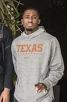 Courtney Ramey is posing in a Texas Longhorns Basketball sweatshirt