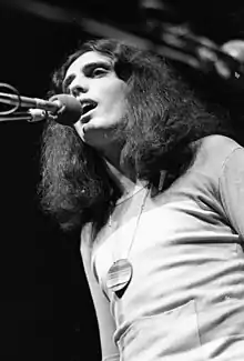 Long haired man singing into a microphone