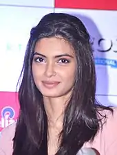 A young Indian woman with long, dark hair smiles at the camera.