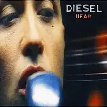 A close-up of the artist's face singing into a blurred microphone. His name is at top right with album title below. At the right side is a blurred image of a guitar's neck with its strings.