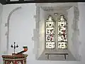 Southeast corner of nave of parish church, showing Perpendicular Gothic window with 1894 glass by Comper & Bucknall and blocked arch of 12th century window