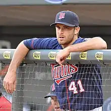 A Minnesota Twins player leaning on the railing of the dugout during a baseball game.