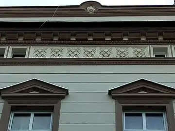 Detail of the upper floors, with lion's head and rosettes