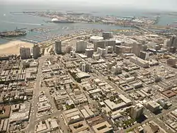 The East Village district of Long Beach, California, is in the right three-quarters of the foreground of this southwest-facing photo (the Alamitos Beach neighborhood makes up the left quarter of the foreground, on the east side of Alamitos Avenue, the diagonal street on the left). Downtown Long Beach is to the right. Queensway Bay/San Pedro Bay are visible, with the Queen Mary and part of the Port of Long Beach in the distance. Catalina Island is faintly visible on the horizon.