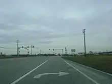 Approaching intersection with IL 60. Road is 2 lanes in each direction, concrete lanes. Traffic signal lies ahead from viewpoint of right turn lane.