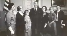 President Lyndon B. Johnson poses in the Oval Office with six white women, all winners of the 1964 Federal Woman's Award; from left to right: Elizabeth Messer, Evelyn M. Anderson, Gertrude Blanch, President Johnson, Patricia van Delden, Margaret Schwartz, and Selene Gifford