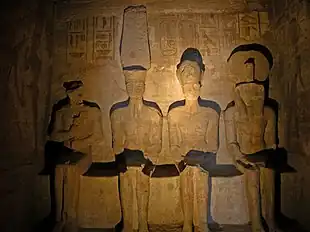 Statues of four seated figures in a dimly lit room