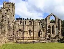 The ruined walls of a large abbey with a tower