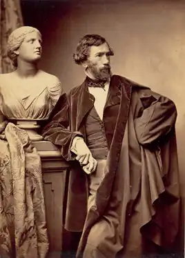 The sculptor François Jouffroy in 1865 wearing the men's fashion of the day, holding his gloves in his hand to show that he could afford them, but did not need them.