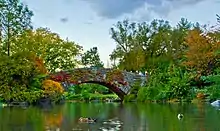 A stone bridge above a lake, with autumn foliage on either side