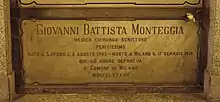 A marble gravestone on the wall of a crypt