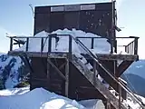 Gobbler's Knob Fire Lookout in a state of disrepair, covered in snow and missing its roof.