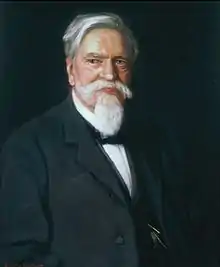 A color portrait of an older gentleman with white hair and a white goatee