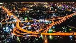 Night photograph looking down at a large elevated road interchange; many billboards along the roads