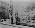 Escape artist Harry Houdini (left) posing near Pluto Spring poster, c.1907