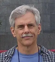 Head of man with short white hair and white moustache.