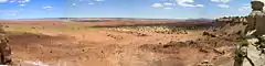 Panorama with coral pick sand and a few rock features on the right side of the image.