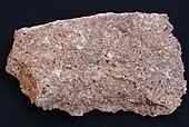 A rough chunk of granite showing grains of red, pink, white, gray and black.