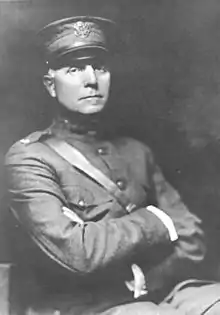 A black-and-white image of a man sitting in a chair in a full military uniform